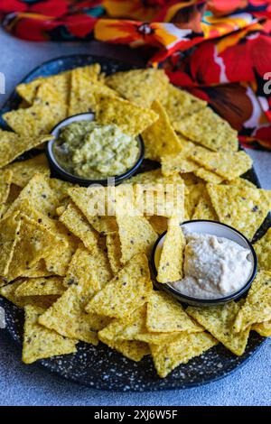 Teller mit Tortilla-Chips mit hausgemachter Guacamole und Sauerrahm-Dip Stockfoto