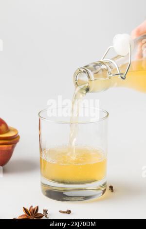 Nahaufnahme der erfrischenden Cider Abfüllung in Glas auf weiße Oberfläche Stockfoto