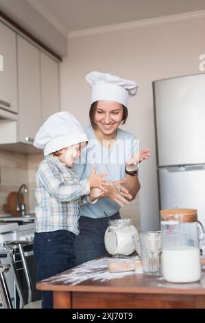 Mutter und Kind Händeklatschen während der Teig in der Küche vorbereiten Stockfoto