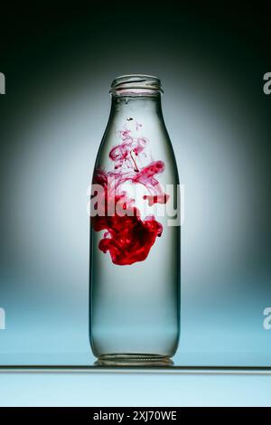 In der Nähe von roter Farbe spritzen in Flasche Wasser Stockfoto