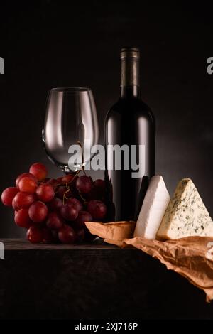 Lecker Rotwein mit Trauben und Käse auf Schwarz Stockfoto
