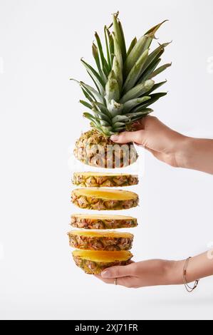 Teilweise mit Blick auf die Frau mit Schneiden Ananas in den Händen isoliert auf weißem Stockfoto