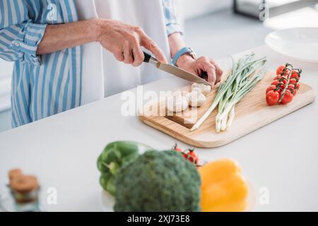 7/8 shot der älteren Dame schneiden Pilze beim Kochen Abendessen am Tresen in der Küche Stockfoto