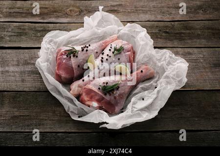 Raw Hähnchenschenkel mit Pfefferkörner und Kalk auf Backpapier auf hölzernen Tischplatte Stockfoto
