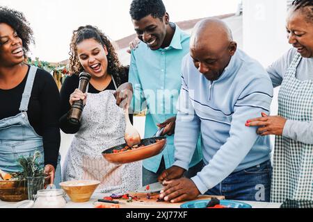 Familie kocht in der Küche, Schwarze Leute bereiten gesundes Mittagessen vor dem Dach Haus. Sommerfeier und kulinarisches Konzept Stockfoto