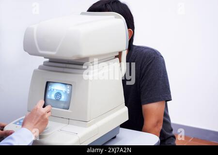 Junger, gutaussehender Asiate macht eine Augenuntersuchung mit einem optischen Augen-Testgerät Stockfoto