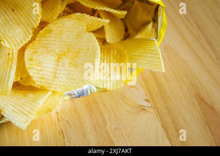 Kartoffelchips, offene Tüte auf Holztisch Stockfoto