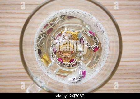 Reinigung Vintage Schmuck Diamant Ring und Armband in Glas auf Holztischhintergrund Stockfoto