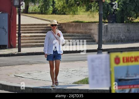 Nicht exklusiv: ODESA, UKRAINE - 13. JULI 2024 - Eine Frau mit Hut und Sonnenbrille trinkt an einem heißen Sommertag ein Getränk, Odesa, Süd-Ukraine. Stockfoto