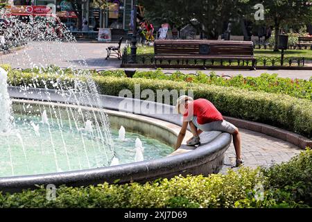 Nicht exklusiv: ODESA, UKRAINE - 13. JULI 2024 - Ein Junge spielt an einem heißen Sommertag an einem Brunnen, Odesa, Süd-Ukraine. Stockfoto