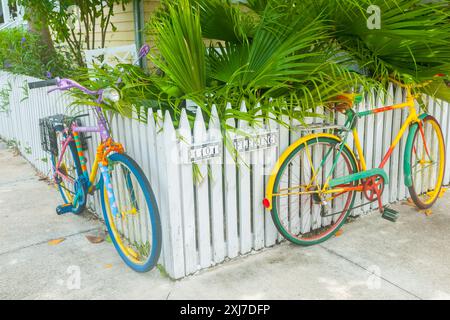 Key West America - 26. Juni 2012; zwei farbenfroh lackierte Fahrräder am weißen Pflückzaun an der Straßenecke befestigt. Stockfoto