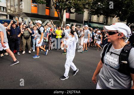 Paris, Frankreich. Juli 2024. Ein olympischer Fackelträger kommt in der Nähe der Menge mit der olympischen Fackel am Place Bastille vorbei. Tausende von Menschen füllten die Straßen von Paris, um die olympische Fackel an ihrem zweiten Tag in der französischen Hauptstadt vorbeiziehen zu sehen. Nach einem emotionalen ersten Tag, der mit den Festlichkeiten zum Bastille Day zusammenfiel, reiste die olympische Fackel erneut über den Place de Bastille in Richtung Place de Republique, ihrem endgültigen Ziel. Quelle: SOPA Images Limited/Alamy Live News Stockfoto