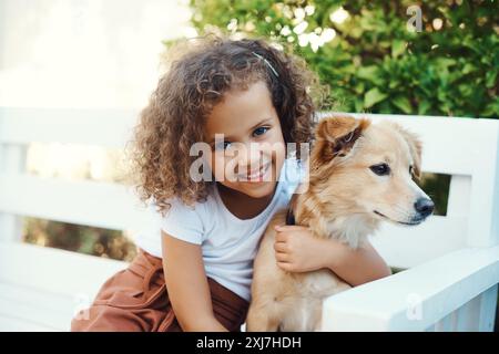 Outdoor, Mädchen und Lächeln für Hund, Porträt und Kleben auf der Bank, zusammen und Pflege von Haustieren oder Hinterhof. Sommer, Haus und Kind mit Welpen, gesund und Stockfoto