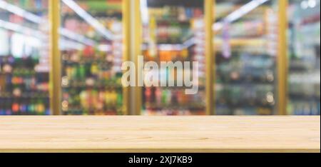 Leere Holztischplatte mit Supermarkt-Kühlschränken mit alkoholfreien Getränkeflaschen auf Regalen abstrakter Unschärfe Hintergrund Stockfoto