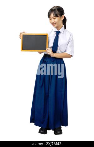 Porträt eines asiatischen Schülers der Junior High School in weiß-blauer Uniform stehend und zeigt leere kleine Tafel isoliert über weißem Hintergrund Stockfoto