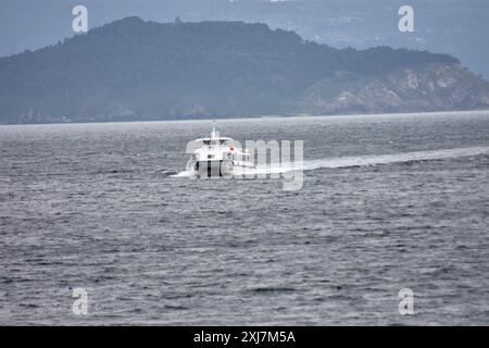 Eine Passagierfähre auf dem Weg zu den malerischen Cies-Inseln in Vigo. Das Schiff gleitet durch das klare blaue Wasser, eingerahmt von der üppigen greene Stockfoto