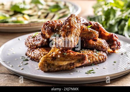 Gegrillte Hähnchenflügel auf einem Teller und gegrillte Zucchini als Beilage. Stockfoto