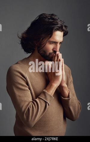 Glaube, beten oder denken mit spirituellem Mann im Studio auf dunklem Hintergrund für den Glauben an Gott oder Jesus. Lob, Vision oder Anbetung mit christlichem Mann in Stockfoto