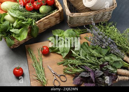 Verschiedene aromatische Kräuter, Gemüse, Scheren und Fäden auf grauem Tisch, Nahaufnahme Stockfoto