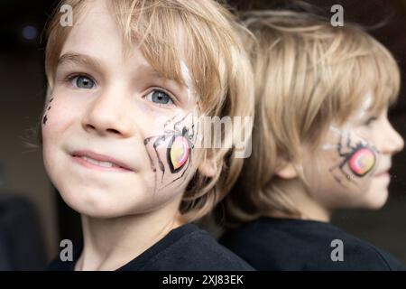 Nahaufnahme des Gesichts eines Jungen mit einer Spinne auf seiner Wange und Reflexion im Spiegel. Halloween-Feier. Trick or Treat. Geheimnisvolles, festliches Bild Stockfoto