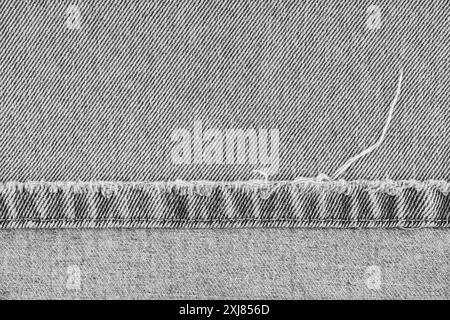 Graue Jeans Hose schäbige Kante auf jeansstoff Hintergrund, Nahaufnahme, Makro. Zerrissene Jeans stich, zerstört, zerrissen. Tapete, Hintergrund, Designdetails. Stockfoto