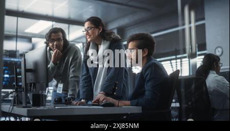 Eine Gruppe von drei jungen indischen Software-Ingenieuren bespricht mithilfe des Computers ein technologisches Projekt im modernen Industriebüro. Gruppe männlicher und weiblicher Wissenschaftler arbeitet im Forschungs- und Entwicklungszentrum Stockfoto