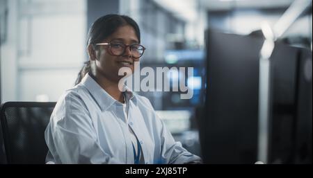 Porträt eines wunderbaren, lächelnden IT-Spezialisten, der für die Kamera im Data Science Laboratory posiert. Junge indische Frau, die in die Kamera schaut. Erfolgreiche Frau, die bei Big Server Farm Cloud Computing Company arbeitet Stockfoto