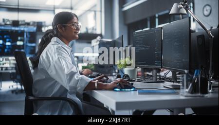 Junge weibliche Künstliche Intelligenz-Ingenieurin, die am Computer in einem Technikbüro arbeitet. Junger indischer Spezialist, der Software-Code für ein innovatives Big Data Blockchain-Projekt schreibt Stockfoto