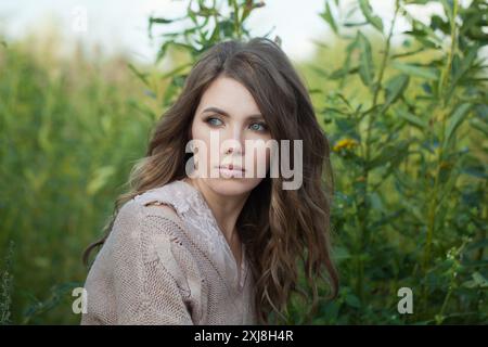 Hübsche gesunde junge Model-Frau mit sauberer frischer Haut, natürlichem Make-up und lockiger Frisur vor grünem Grashintergrund, Outdoor-Porträt Stockfoto