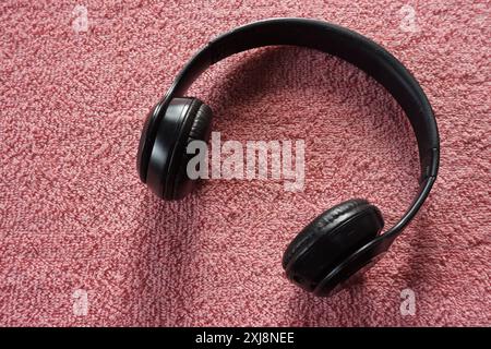 Nahaufnahme des schwarzen kabellosen bluetooth-Kopfhörers auf rotem Hintergrund Stockfoto