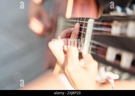 Nahaufnahme einer Frauenhand, die Gitarre spielt. Ihre Hand macht einen Akkord. Stockfoto