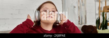 Ein kleines Mädchen mit Down-Syndrom hört gern zu Hause Musik. Stockfoto