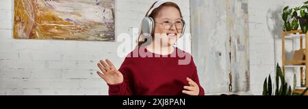 Ein kleines Mädchen mit Down-Syndrom genießt Musik und tanzt in ihrem Wohnzimmer. Stockfoto