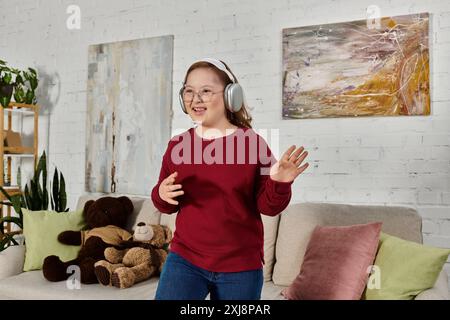 Ein kleines Mädchen mit Down-Syndrom, das Kopfhörer trägt, tanzt in ihrem Haus. Stockfoto