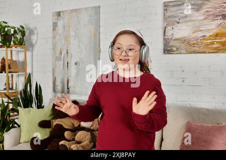 Ein kleines Mädchen mit Down-Syndrom tanzt zu Musik, während es zu Hause Kopfhörer trägt. Stockfoto