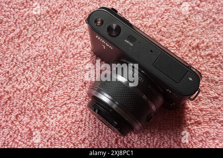 Terengganu, Malaysia - 2. August 2024 : Nahaufnahme der spiegellosen nikon 1 j1 Kamera auf rotem Hintergrund. 1 Zoll Kompaktkamera. Austauschbares Kameraobjektiv. Stockfoto