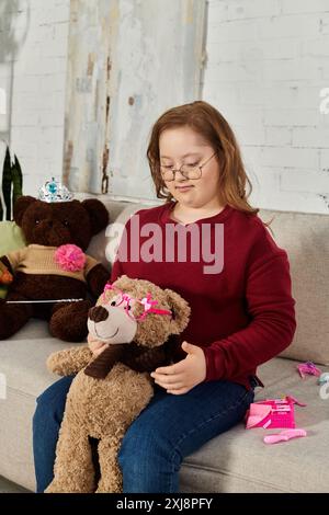 Ein kleines Mädchen mit Down-Syndrom spielt zu Hause mit ihrem Teddybären. Stockfoto