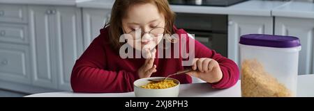 Ein kleines Mädchen mit Down-Syndrom genießt zu Hause eine Mahlzeit. Stockfoto