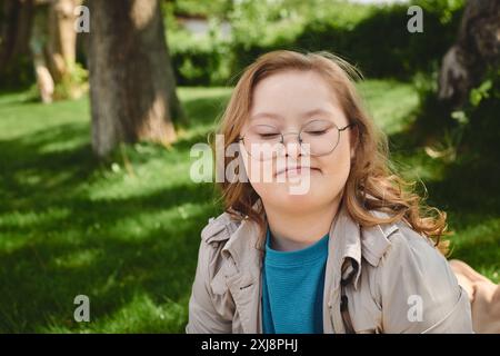 Ein kleines Mädchen mit Down-Syndrom genießt einen ruhigen Moment im Freien. Stockfoto