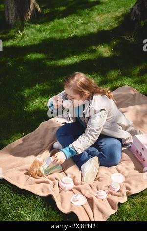 Ein kleines Mädchen mit Down-Syndrom genießt eine Teeparty im Freien. Stockfoto