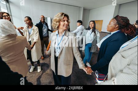 Reife Geschäftsfrau leitet ein vielfältiges Team in einem erfolgreichen Workshop, der sich auf Teamarbeit und Zusammenarbeit in einer modernen Büroumgebung konzentriert. Stockfoto