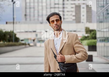 Porträt eines jungen indischen Geschäftsmannes, der in einem Anzug gekleidet ist und eine moderne Sonnenbrille trägt und in die Kamera schaut. Stockfoto