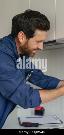 Professioneller Elektriker, der beim Installieren einer neuen Steckdose in der Küche einen Schraubendreher verwendet Stockfoto