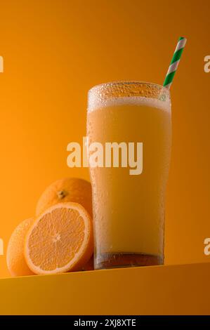 Ein Glas frischer Orangensaft mit lebendigen Zitrusfrüchten auf hellgelbem Hintergrund, der erfrischend, gesund und natürlich wirkt. Stockfoto