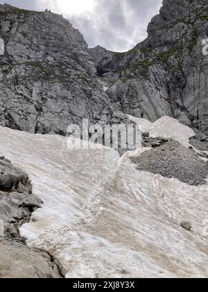 Garmisch Partenkirchen, Deutschland. Juli 2024. Auf dem Klettersteig auf der Alpspitze oberhalb von Garmisch-Partenkirchen sind Anfang Juli noch Spuren von überquerenden Bergsteigern in den Schneefeldern zu sehen. (An dpa: 'Notruf in den Bergen: Klimakrise beeinflusst Hütten und Wanderwege') Credit: Sabine Dobel/dpa/Alamy Live News Stockfoto