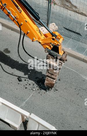 Ein hydraulischer Schlaghammer am Bagger, der verwendet wird, um den Asphalt einer Straße zu zerbrechen Stockfoto