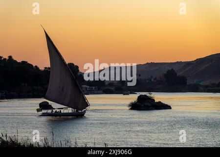 Felucca (traditionelles ägyptisches Segelboot) auf dem Nil bei Sonnenuntergang in Assuan, Ägypten Stockfoto