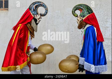 Das Entroido de Xinzo, eine der lebhaftesten Karnevalsfeiern Galiciens, zeigt Teilnehmer in traditioneller Kleidung, die als „Pantallas“ bekannt ist. Diese Figuren stammen aus alten Ritualen, um böse Geister abzuwehren. Sie tragen ausgeklügelte Masken, bunte Schärpen und Glocken. Ein markantes Element sind die großen aufgeblasenen Tierblasen oder „veciñas“, die sie tragen und verwenden, um die Zuschauer spielerisch anzuzapfen und den Festlichkeiten eine lebendige und einzigartige Note zu verleihen. Die Pantallas sind traditionelle Masken aus Pappe, Zeitung, Filz und Paste aus Mehl und Wasser, verziert mit Astralmotiven oder totemischen Tieren Stockfoto