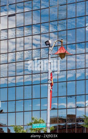 NYC Chinatown: Dekoratives Straßenlicht „Chinatown Pagoda Pendant“ vor dem Hintergrund von Wolken, die in der glashäutigen 2 Mott Street reflektiert werden. Stockfoto