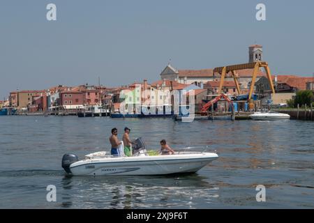 Pellestrina ist eine italienische Insel in der Lagune von Venedig. Kirche Allerheiligen auf der Skyline. Lokale Urlauber in ihrem Motorboot. Pellestrina Italien 2024 2020er Jahre HOMER SYKES Stockfoto